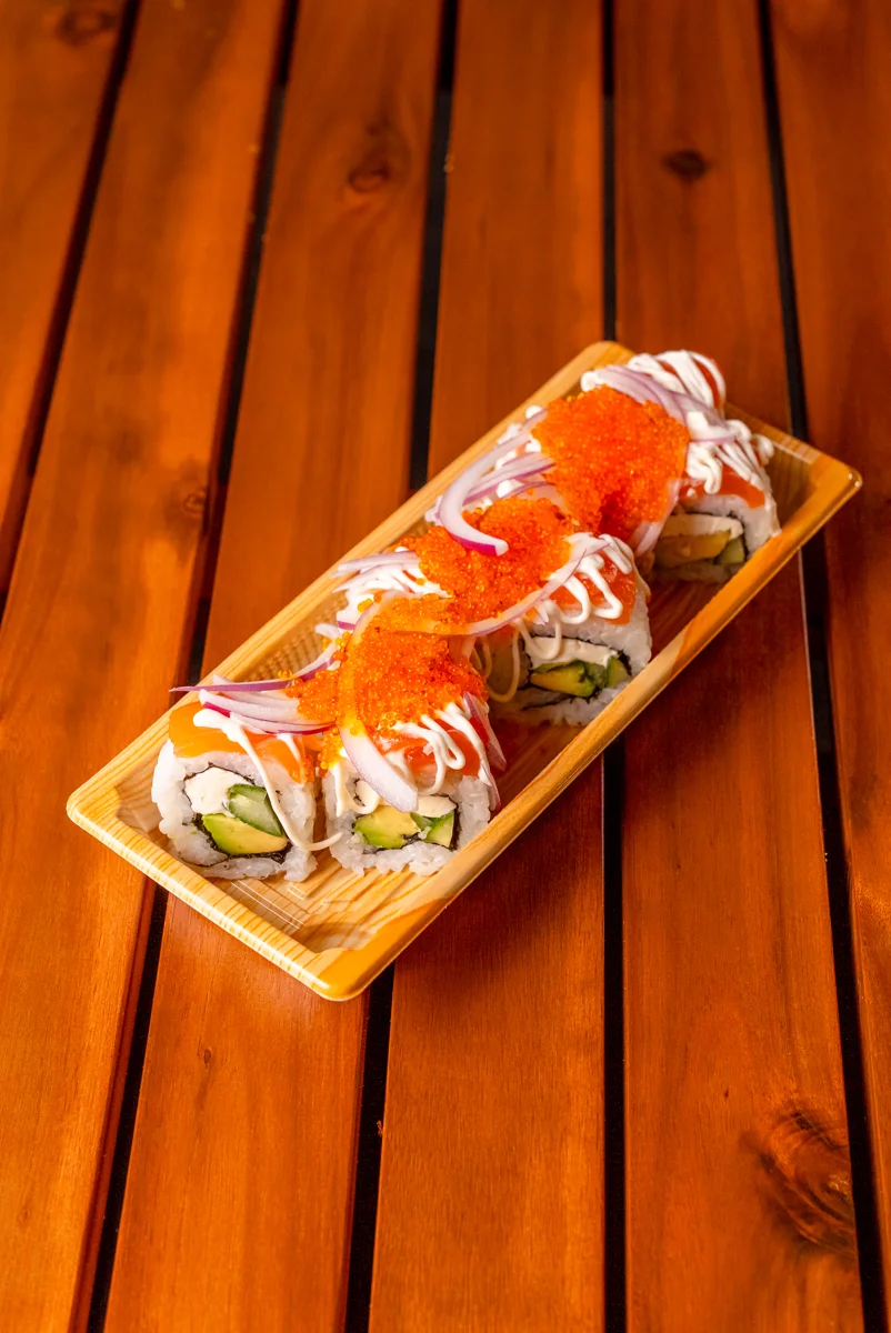 Sushi rolls topped with salmon, onion and sauce