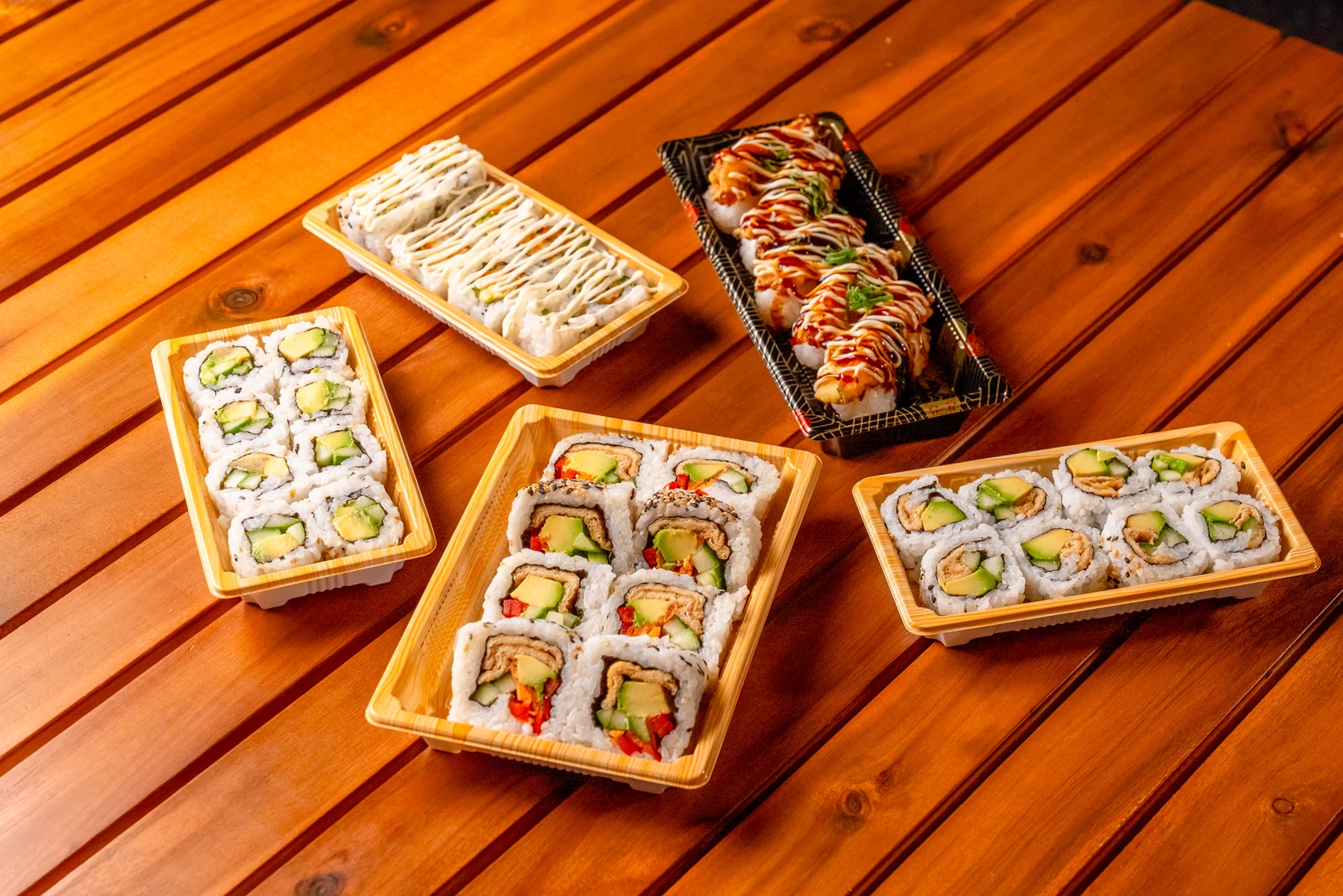 A spread of Skinny Sushi rolls on a warm timber table